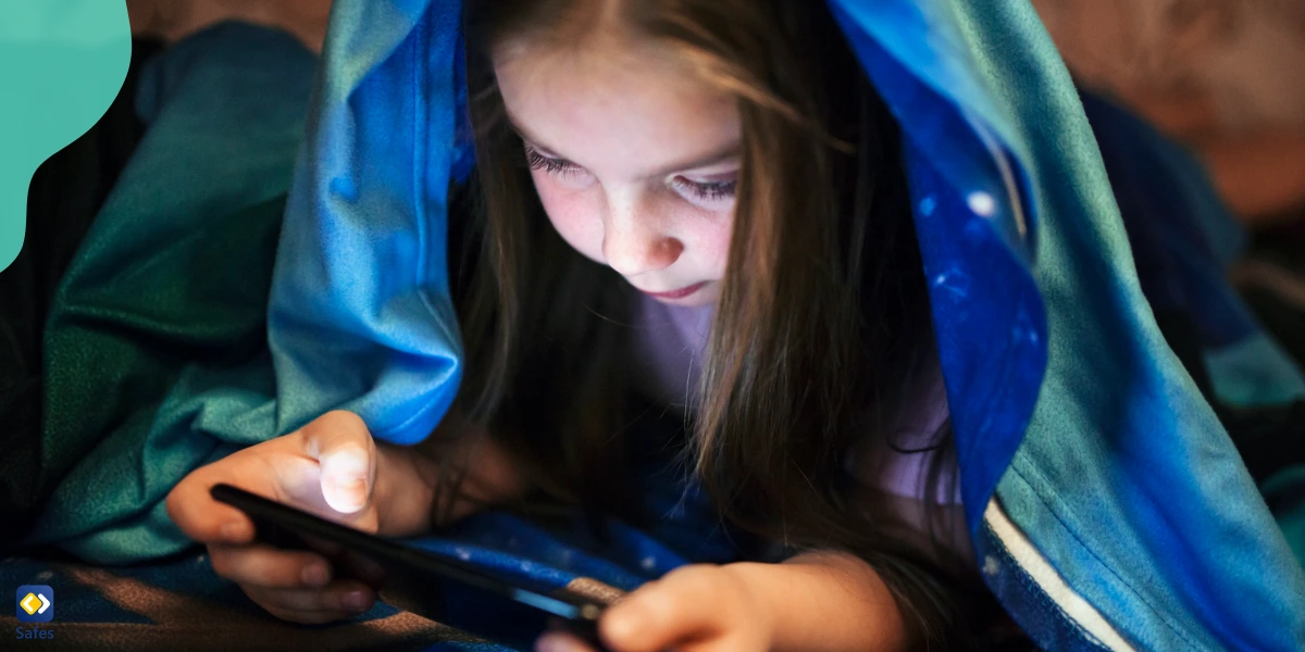 Ein junges Mädchen liest in ihrem Bett ein Buch auf ihrem Handy. Ihre Eltern nutzten Safes, um ihr Zugang zu digitalen Büchern zu verschaffen, sogar im Bett